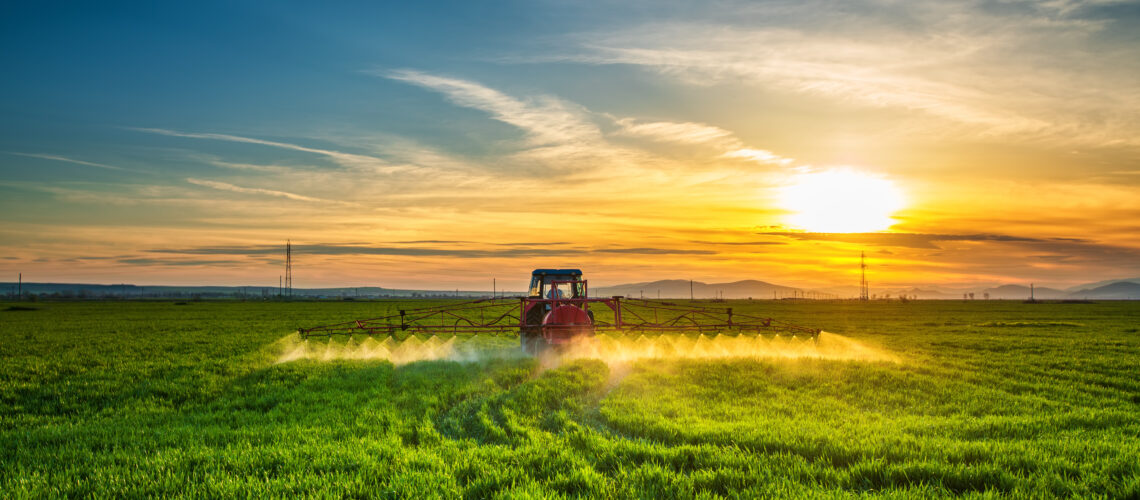 Farming tractor plowing and spraying on field.