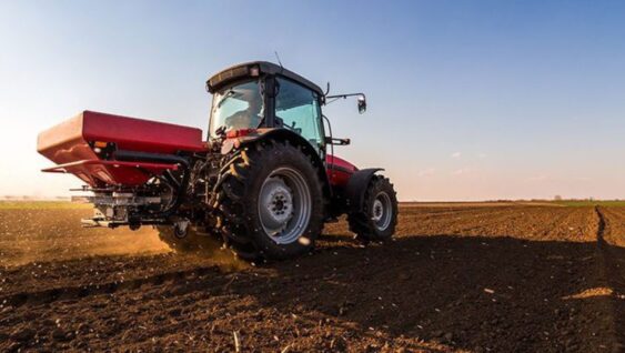 A tractor spreading fertilizer in a field.