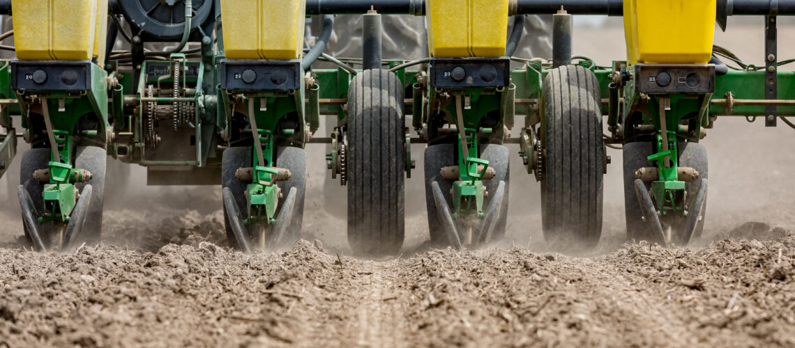 Closeup of tractor and planter in farm field planting corn or soy.