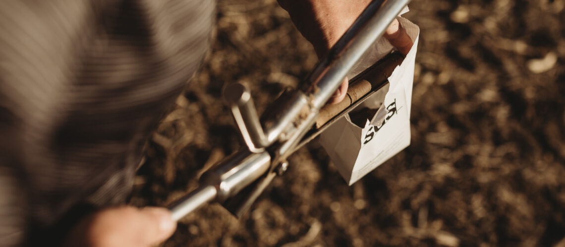 A farmer placing a soil sample in paper bag.