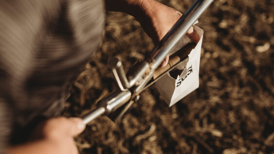 A farmer placing a soil sample in paper bag.