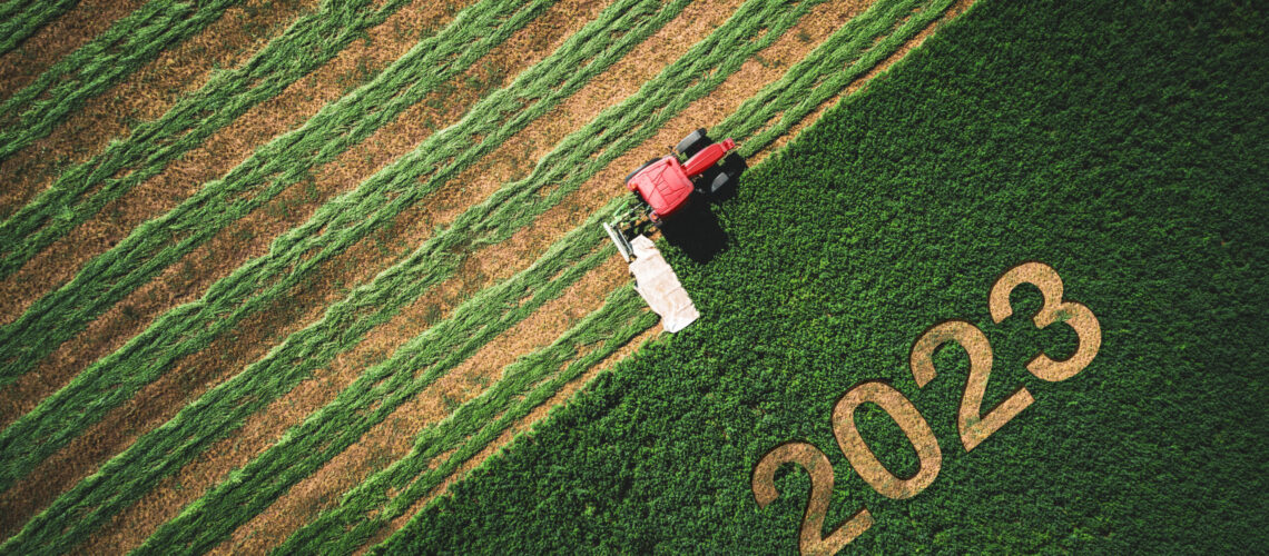 2023 Happy Ney Wear concept and red tractor mowing green field.