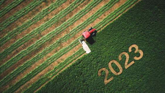 2023 Happy Ney Wear concept and red tractor mowing green field.