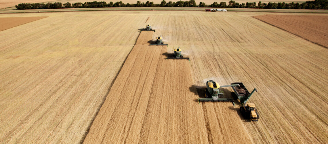Four harvesters combing on a prairie landscape in formation
