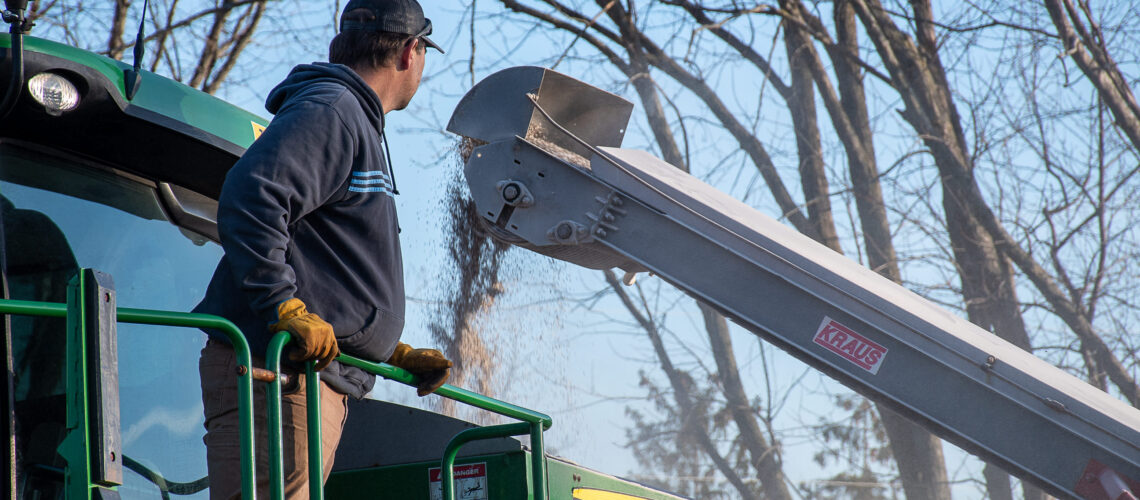 farmer loading fertilizer into tractor using belt loader
