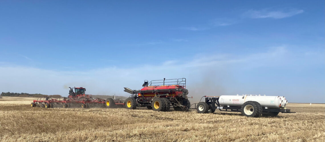A farmer seeding his crop using Anhydrous Ammonia for fertilizer on a warm spring morning
