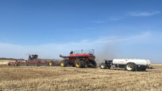 A farmer seeding his crop using Anhydrous Ammonia for fertilizer on a warm spring morning