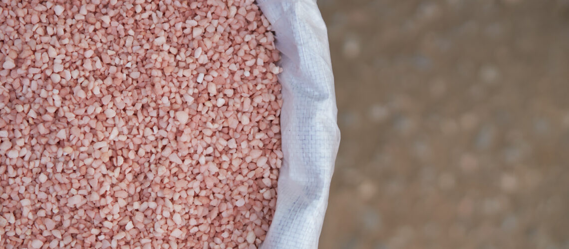 Potassium chloride fertilizer granules sitting in a storage bag to represent the growing demand for potash.