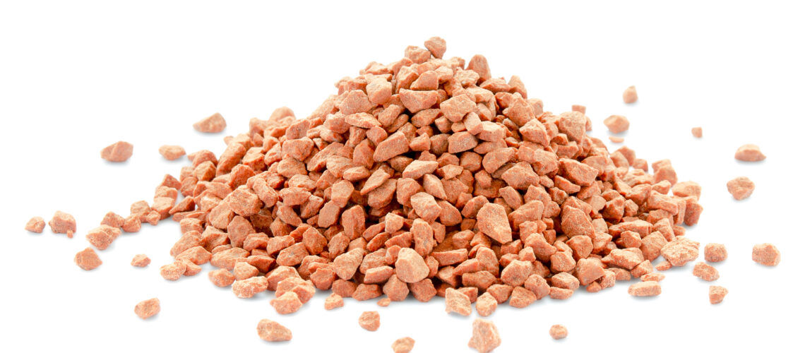 Heap of potassium chloride granules on a white background.