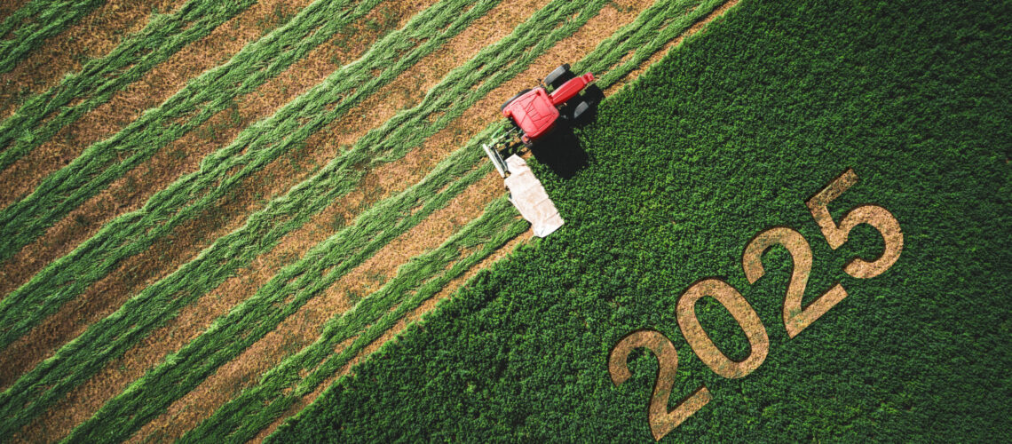 Red tractor harvesting a field with the year 2025 carved into the crop, symbolizing another year of crop nutrition insights harvested for growers.